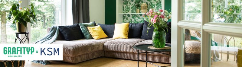 visual of a couch in a living room, with a plant and flower, the wall is wrapped with Grafityp film